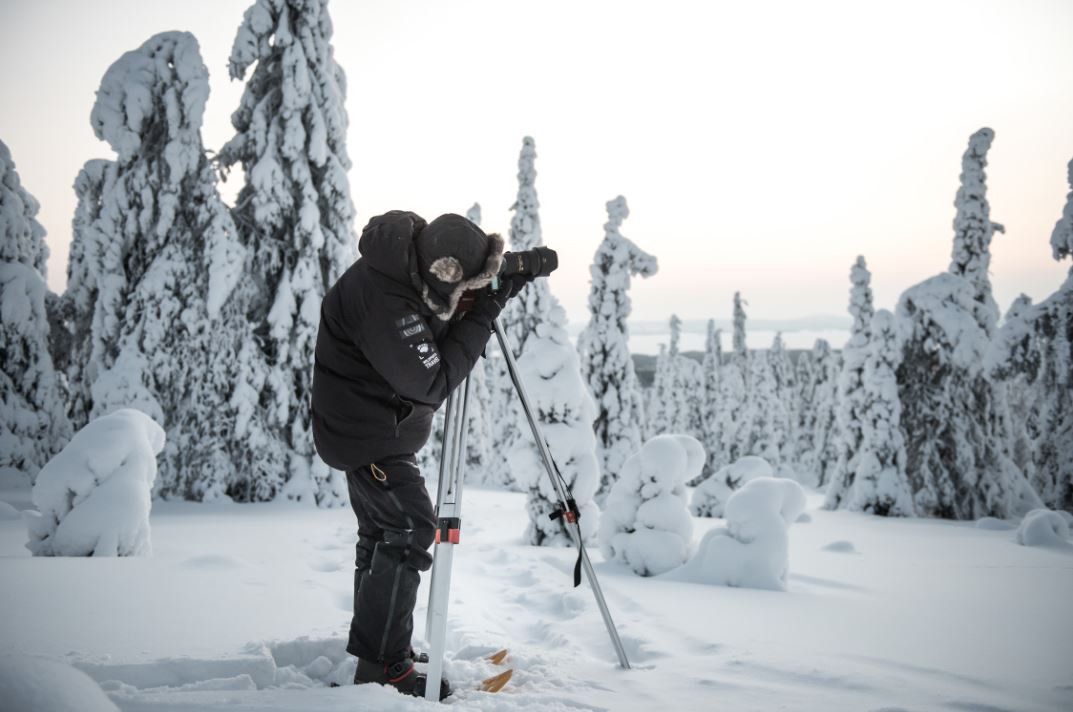 A photographer in snowy forest.