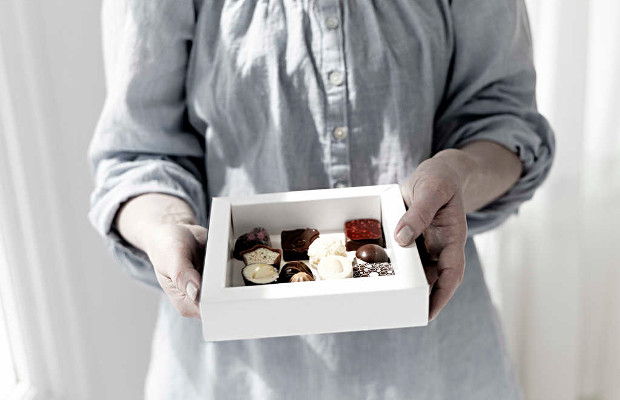 A woman holding a carton board box with chocolates.