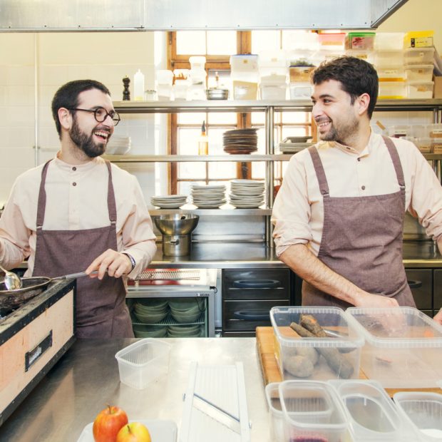 Two male chefs working side by side at a restaurant kitchen.