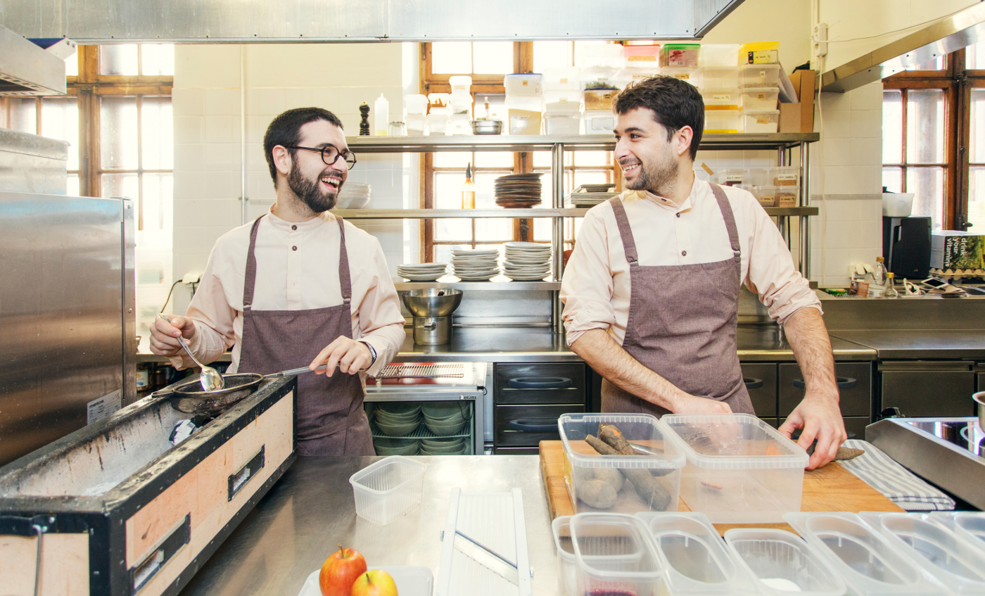 Two male chefs working side by side at a restaurant kitchen.