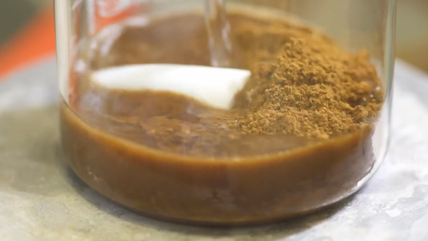 Brown lignin powder and water in a transparent glass.